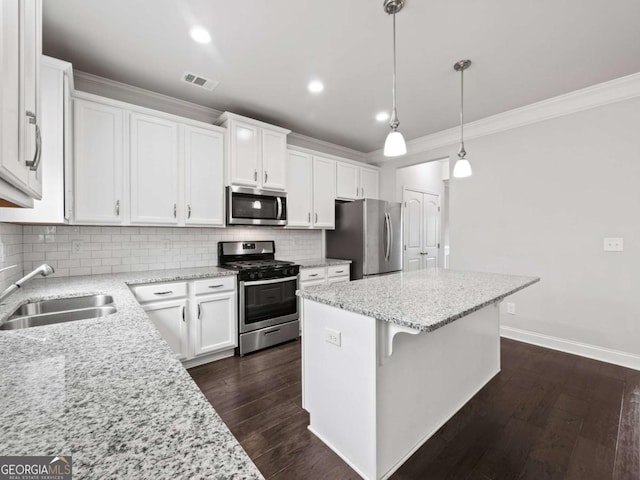 kitchen featuring a center island, tasteful backsplash, visible vents, appliances with stainless steel finishes, and a sink