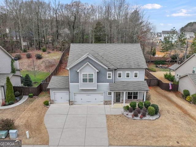 traditional-style house featuring driveway, a porch, an attached garage, and fence