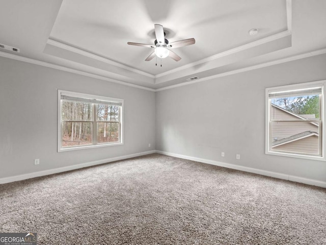 carpeted empty room featuring baseboards, visible vents, and a raised ceiling