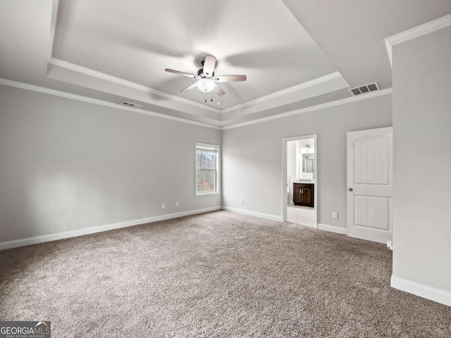 carpeted spare room with baseboards, visible vents, a tray ceiling, and a ceiling fan