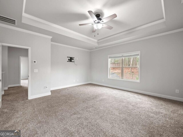 carpeted empty room with baseboards, a raised ceiling, a ceiling fan, and ornamental molding