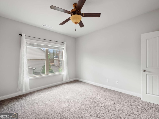 carpeted spare room featuring baseboards, visible vents, and a ceiling fan