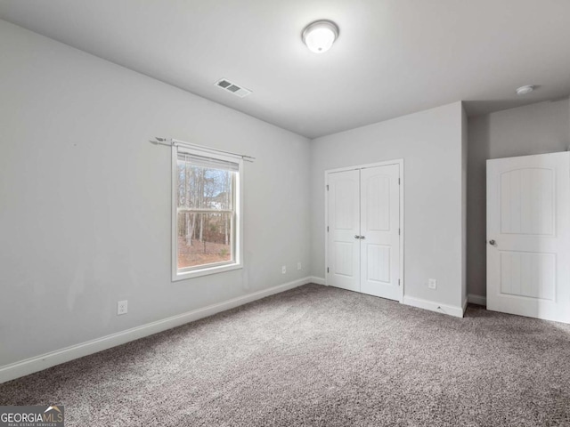 unfurnished bedroom with carpet floors, baseboards, visible vents, and a closet