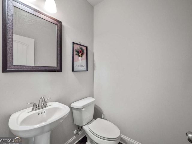 bathroom featuring toilet, baseboards, and a sink