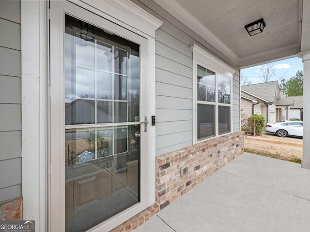 doorway to property with brick siding and a porch