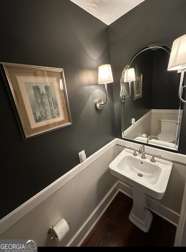 bathroom with toilet, a sink, and wood finished floors