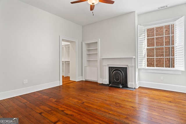 unfurnished living room with hardwood / wood-style flooring, a fireplace with flush hearth, visible vents, and baseboards