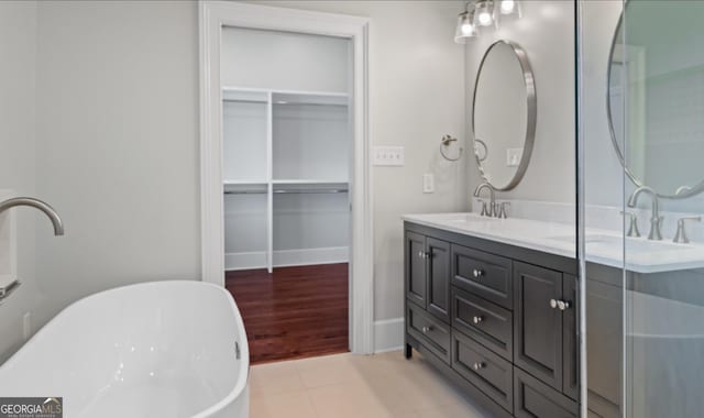 bathroom with a freestanding bath, double vanity, tile patterned flooring, and a sink