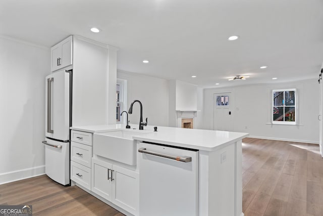 kitchen featuring light wood finished floors, high end fridge, light countertops, a sink, and dishwasher