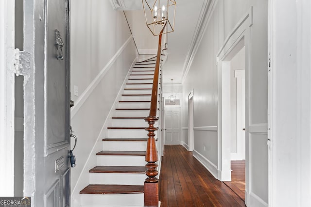 stairway with a chandelier, crown molding, and hardwood / wood-style flooring