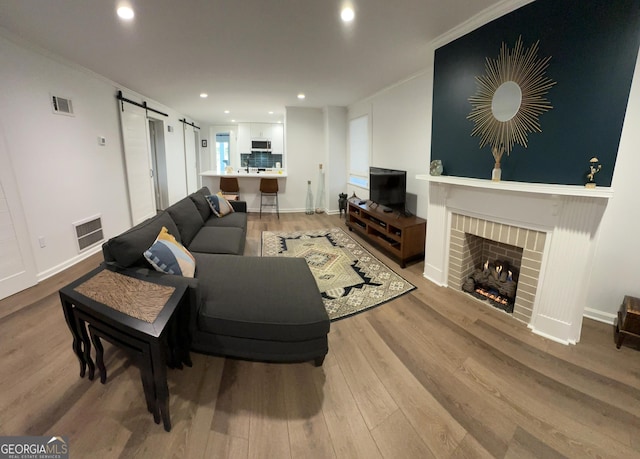 204 E Liberty St, Savannah, GA 31401 - living room with a barn door, light wood finished floors, crown molding, recessed lighting, and a brick fireplace