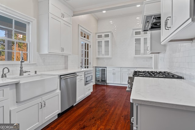 kitchen with white cabinets, wine cooler, light stone counters, built in microwave, and stainless steel dishwasher