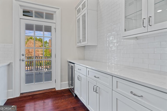 kitchen with light stone counters, white cabinets, dark wood finished floors, and glass insert cabinets