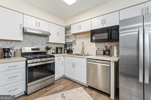 kitchen featuring under cabinet range hood, appliances with stainless steel finishes, light countertops, and a sink