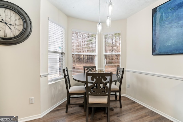 dining room with a textured ceiling, plenty of natural light, wood finished floors, and baseboards