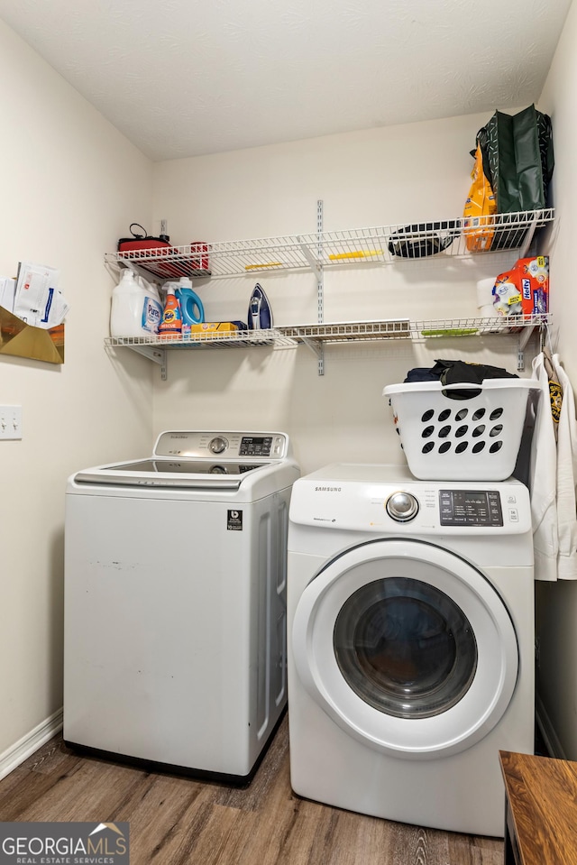 clothes washing area with laundry area, baseboards, separate washer and dryer, and wood finished floors