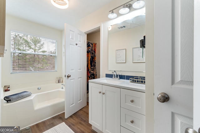 full bath with visible vents, a garden tub, vanity, and wood finished floors