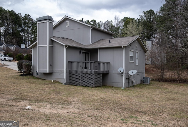 back of house featuring a yard, a shingled roof, a chimney, and cooling unit