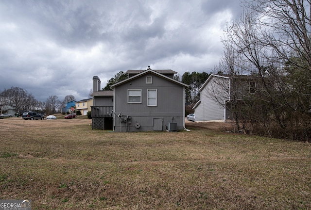 rear view of property featuring a lawn and central air condition unit