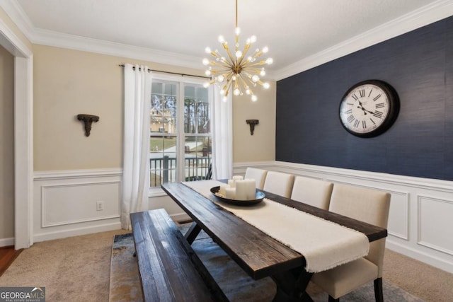 carpeted dining room with an accent wall, a decorative wall, crown molding, and wainscoting