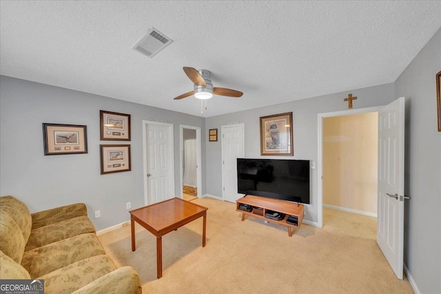 living room featuring visible vents, light carpet, ceiling fan, a textured ceiling, and baseboards