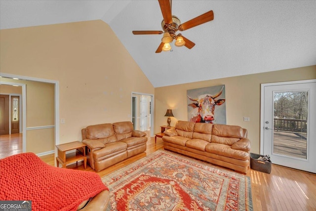 living room with ceiling fan, high vaulted ceiling, french doors, and light wood-style flooring