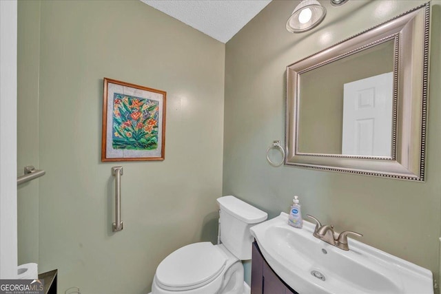 bathroom with toilet, a textured ceiling, and vanity