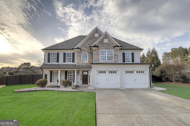 view of front facade featuring an attached garage, fence, driveway, stone siding, and a front lawn