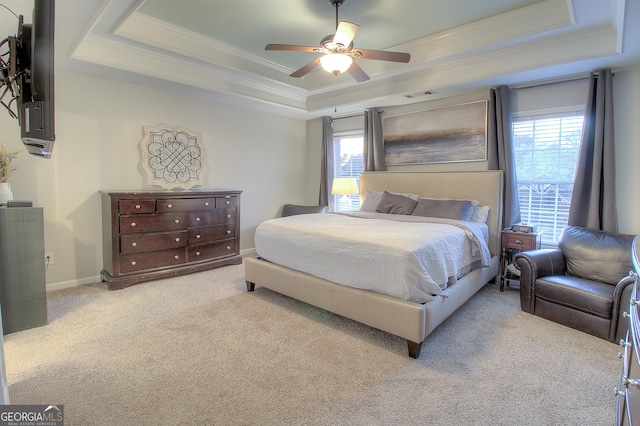 carpeted bedroom featuring baseboards, multiple windows, a tray ceiling, and ornamental molding