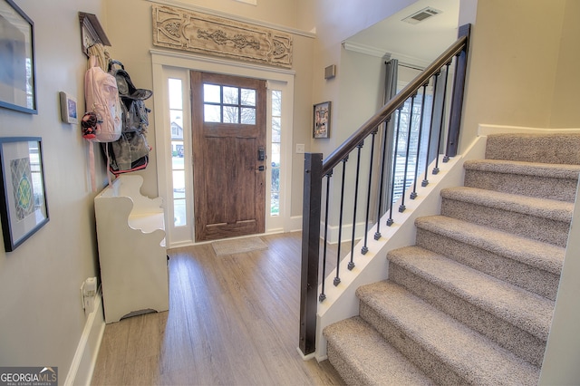 entryway with light wood finished floors, stairway, visible vents, and baseboards