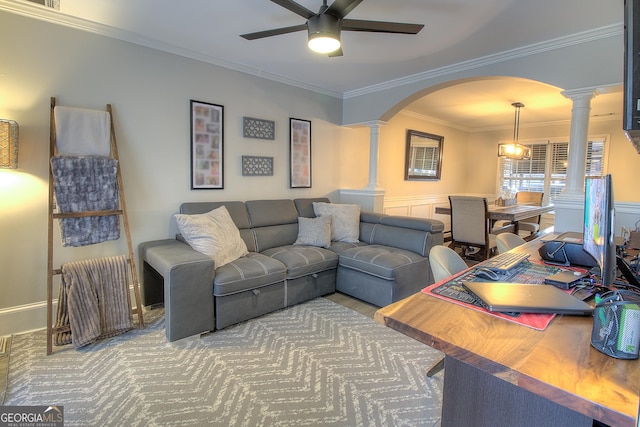 living area featuring ornate columns, ceiling fan, arched walkways, and ornamental molding