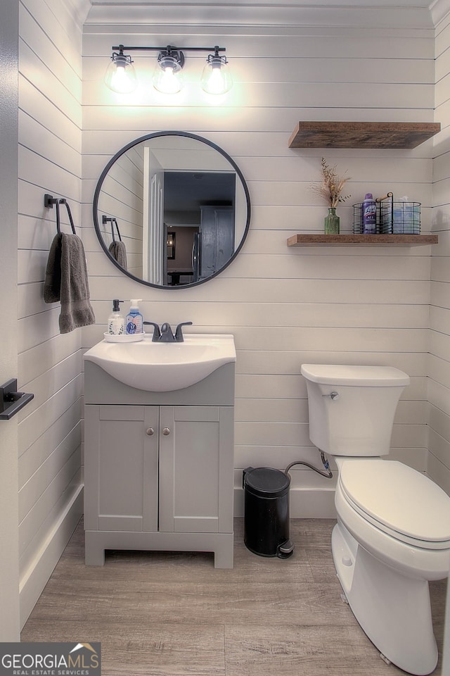 half bath featuring vanity, toilet, and wood finished floors