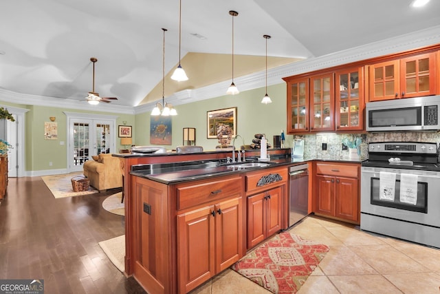 kitchen with vaulted ceiling, appliances with stainless steel finishes, a sink, and crown molding