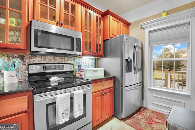 kitchen with tasteful backsplash, glass insert cabinets, appliances with stainless steel finishes, brown cabinets, and crown molding