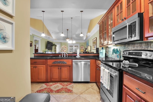 kitchen with tasteful backsplash, lofted ceiling, appliances with stainless steel finishes, decorative light fixtures, and a peninsula