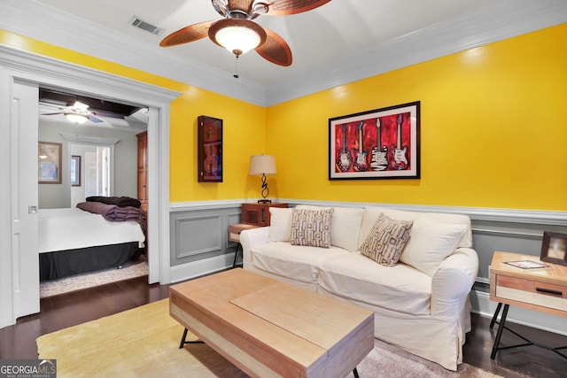 living area featuring ornamental molding, wainscoting, visible vents, and wood finished floors