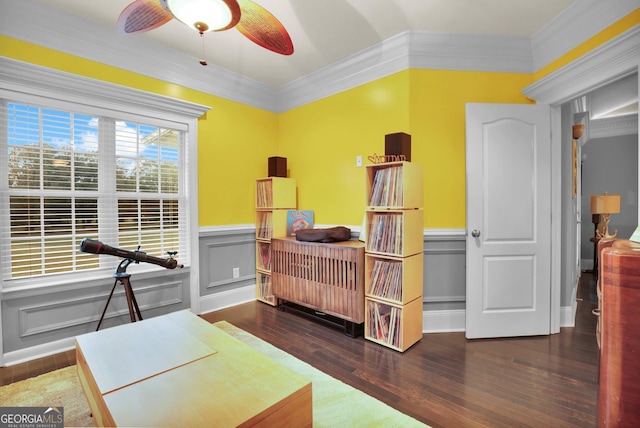 bedroom with ornamental molding, a wainscoted wall, a decorative wall, and wood finished floors