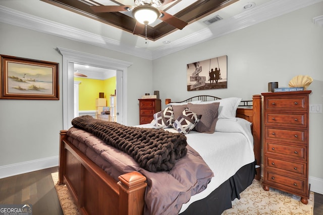 bedroom with a tray ceiling, crown molding, visible vents, light wood-style floors, and baseboards