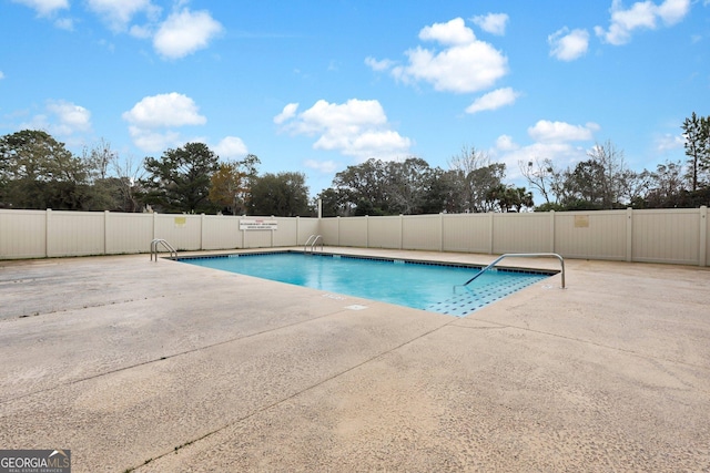 community pool with a patio area and fence