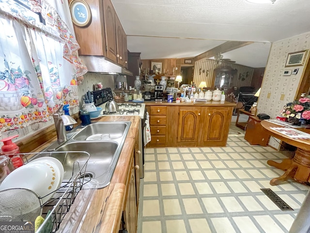 kitchen with range, light floors, a peninsula, light countertops, and under cabinet range hood