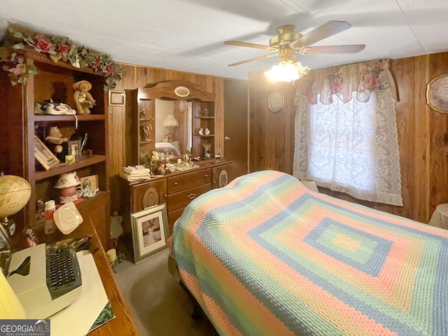 bedroom with ceiling fan, carpet floors, and wooden walls