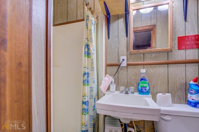 bathroom featuring a sink, wood walls, and radiator heating unit