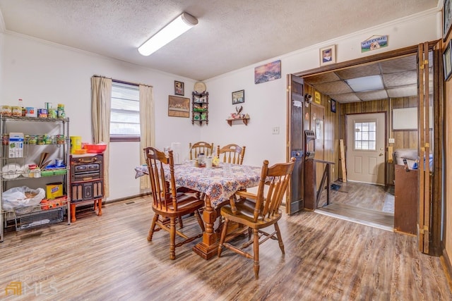 dining room featuring a textured ceiling, ornamental molding, and wood finished floors