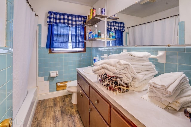 bathroom featuring toilet, vanity, wood finished floors, and tile walls