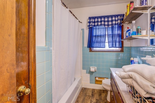 bathroom featuring toilet, wood finished floors, tile walls, and shower / bathtub combination with curtain