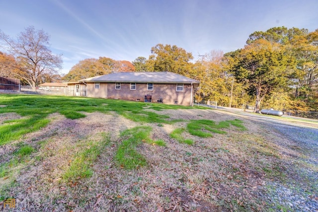 exterior space with crawl space, brick siding, a yard, and fence