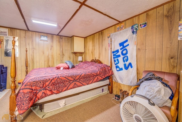 bedroom with a textured ceiling, wood walls, and carpet flooring