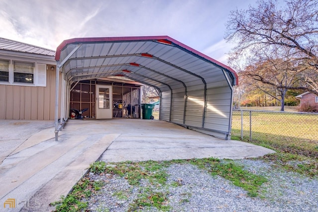 view of parking with driveway, a carport, and fence