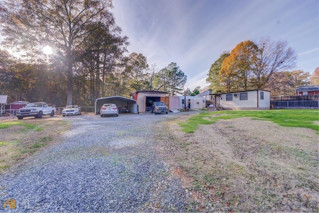 view of front of home with gravel driveway, fence, a carport, and a front yard