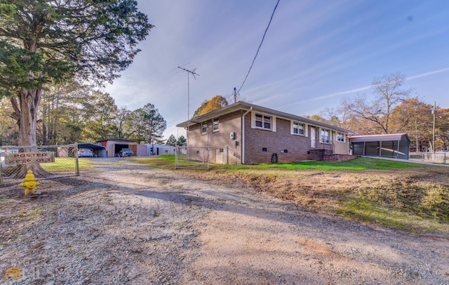 view of side of home featuring driveway, brick siding, crawl space, and fence